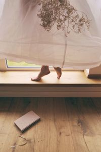 Low section of woman with mobile phone sitting on hardwood floor