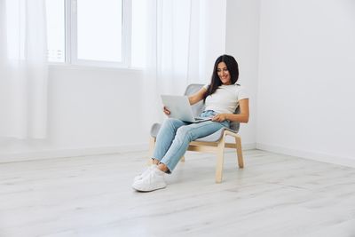 Full length of woman sitting on bed at home