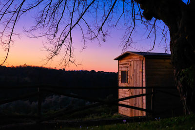 House on field against sky at sunset