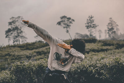 Woman with arms raised on field against sky