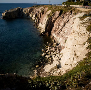 Scenic view of cliff by sea against sky