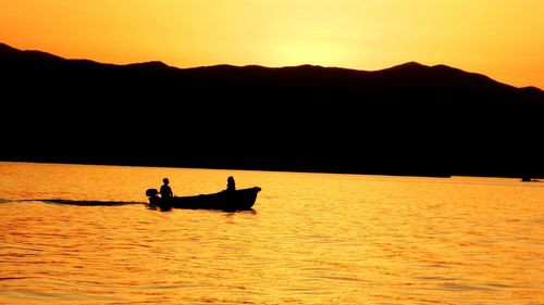 Boat sailing in sea at sunset