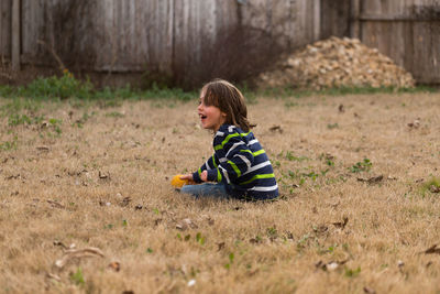 Side view of boy sitting on field