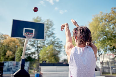 Rear view of woman playing with ball against sky