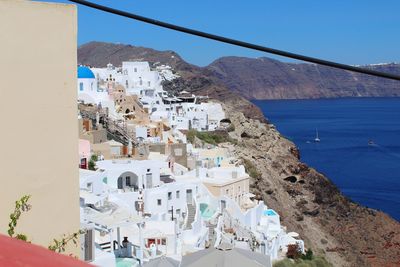 Looking down on the coast of santorini greece with a beautiful blue sky and mountains.