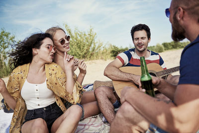 Happy friends enjoying picnic at beach