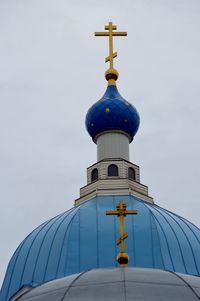 Low angle view of cross by building against sky