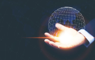 Digital composite image of hand holding globe