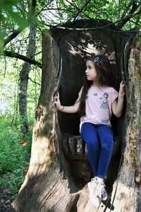 Full length of girl sitting in hollow tree