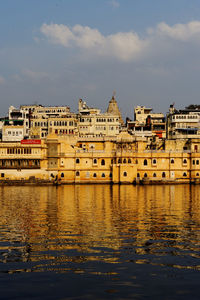 Buildings by river against sky in city