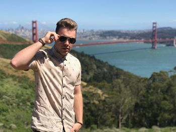 Young man wearing sunglasses standing against clear sky