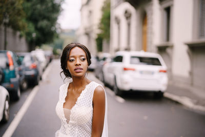 Portrait of young woman standing on street in city