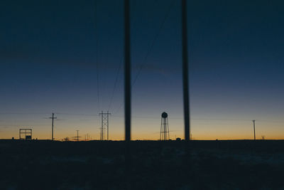 Low angle view of silhouette electricity pylon against clear sky