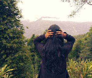 Rear view of woman standing against plants