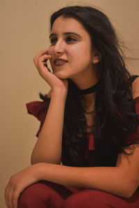 Beautiful young woman sitting against gray background