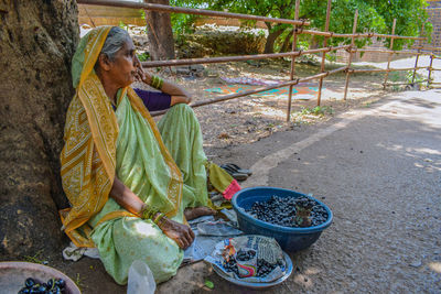 Midsection of woman holding food while sitting outdoors