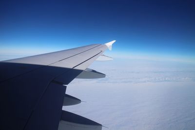 Close-up of airplane wing against blue sky