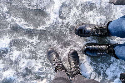 Two girls looking down at feet. frozen lake or river. feet on ice. wearing snow shoes and standing 