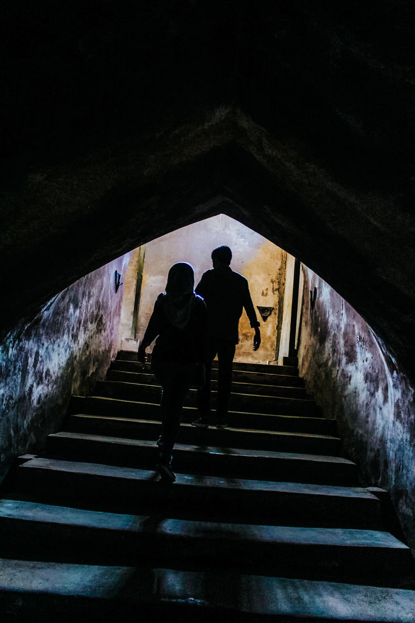 REAR VIEW OF COUPLE WALKING ON STAIRCASE