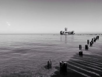 Distance shot of boat in calm sea against clear sky