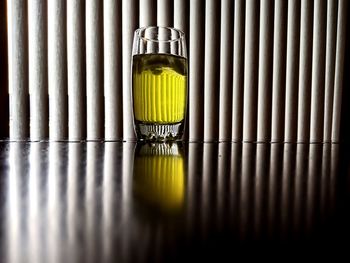 Surface level of glass with beer on table against curtain