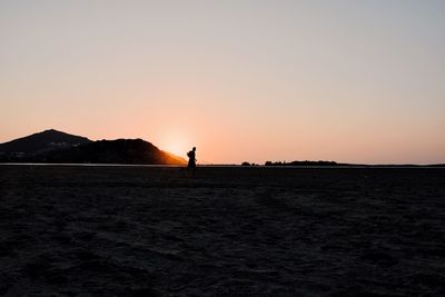 Silhouette man standing on desert against clear sky