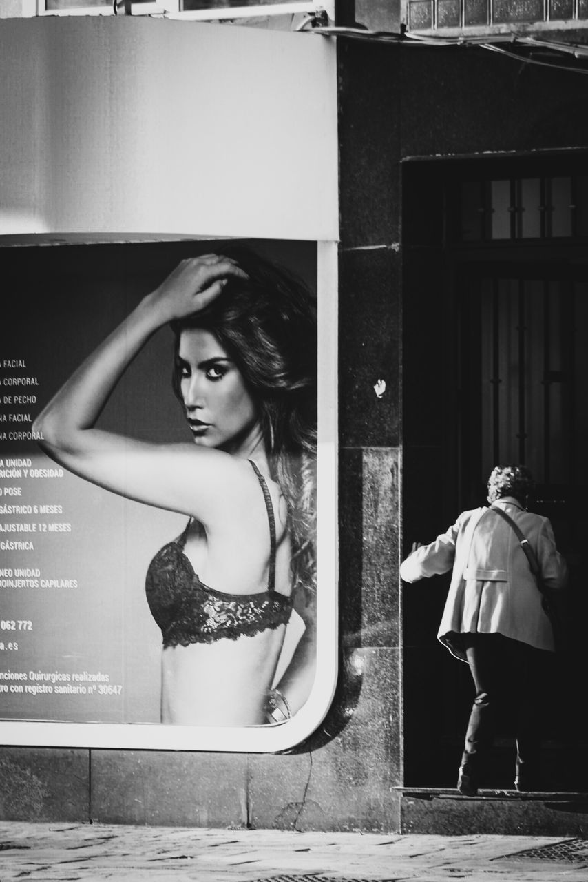 YOUNG WOMAN STANDING AGAINST THE WALL