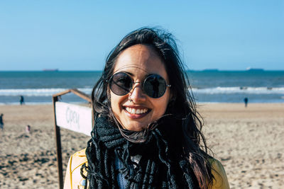 Portrait of smiling young woman wearing sunglasses at beach