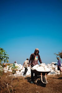 People standing on land against clear blue sky