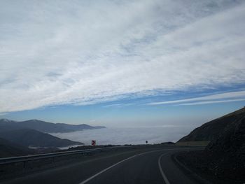 Road by mountains against sky