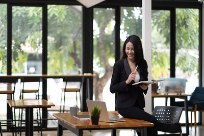Portrait of smiling young woman using laptop on table