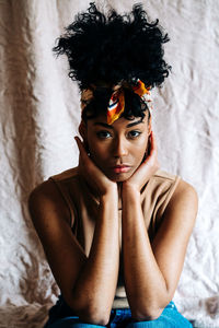 Portrait of young woman sitting against wall
