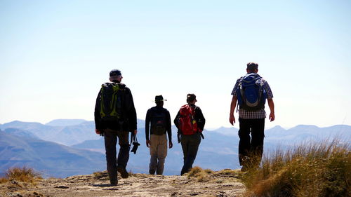 Rear view of people walking on mountain against sky