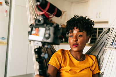 Cheerful young african american female blogger recording video while preparing content for social networks at home