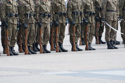 Low section of soldiers standing on footpath in city