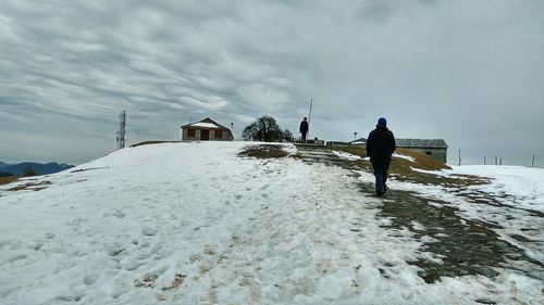 Rear view of man walking on snow covered landscape