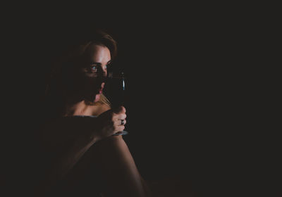 Portrait of woman looking away over black background