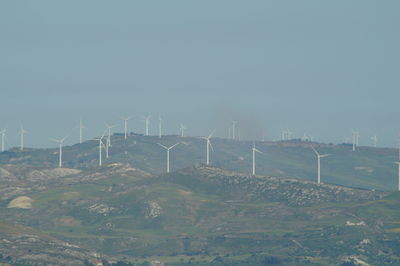 Windmills on field against sky