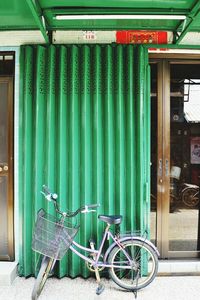 Bicycle parked against green wall