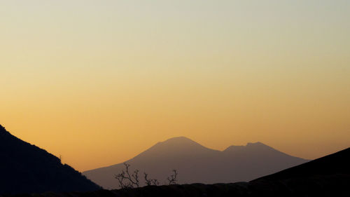 Scenic view of silhouette mountains against clear sky during sunset