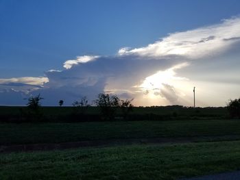 Scenic view of grassy field against sky at sunset