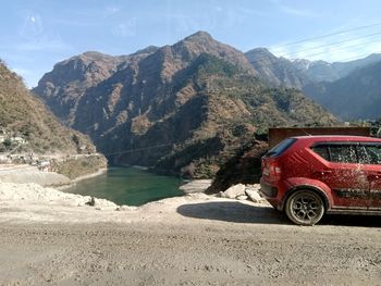 Red car on mountain by road against sky