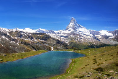 Scenic view of snowcapped mountains against blue sky