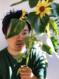 Portrait of young man with flowers and leaves