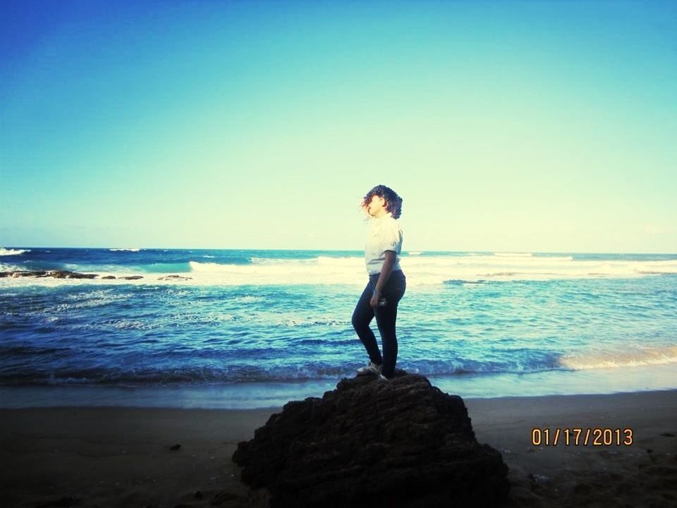 sea, beach, shore, horizon over water, water, full length, clear sky, lifestyles, leisure activity, standing, copy space, rear view, casual clothing, rock - object, sand, tranquility, scenics, beauty in nature