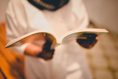 Midsection of woman holding book in home