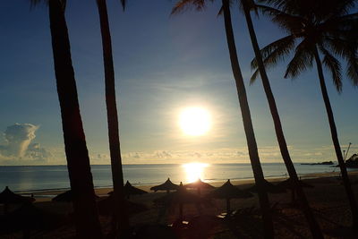 Silhouette palm trees on beach against sky during sunset