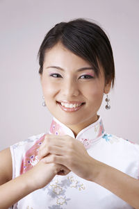 Portrait of happy young woman gesturing against gray background