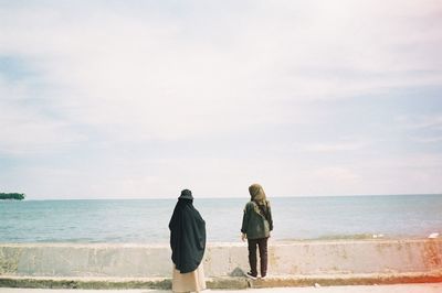 Rear view of women looking at sea against sky