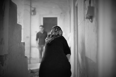 Rear view of man and woman standing against wall